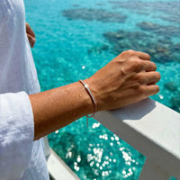 Thumbnail for Rose gold Crystal Bar Bracelet worn on a wrist resting on a railing above turquoise sea