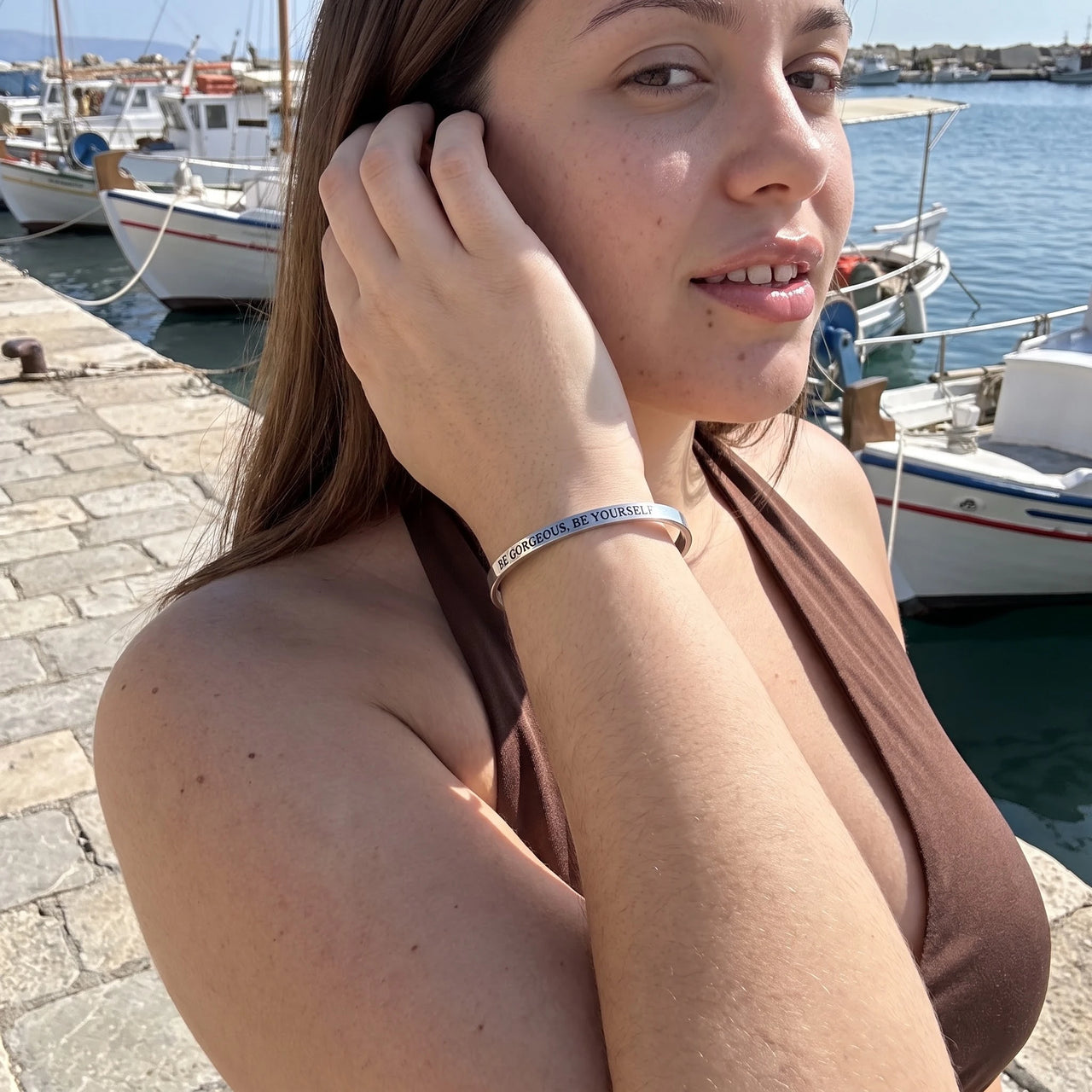 Woman gently touching her Be Gorgeous, Be Yourself bracelet in silver | SKU: bgby-wg