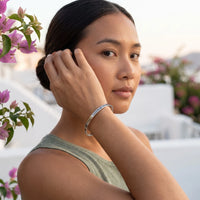 Thumbnail for Woman gently touching her Be The Unique Version Of Yourself bracelet in silver | SKU: btuvoy-wg