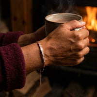 Thumbnail for Rose gold Crystal Bar Bracelet worn while holding a warm mug in front of a fire