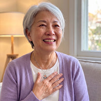 Thumbnail for Smiling grey-haired woman in a lilac cardigan, hand on her heart, wearing the silver secret drop photo necklace | SKU: TPH-DRPN-SILVER