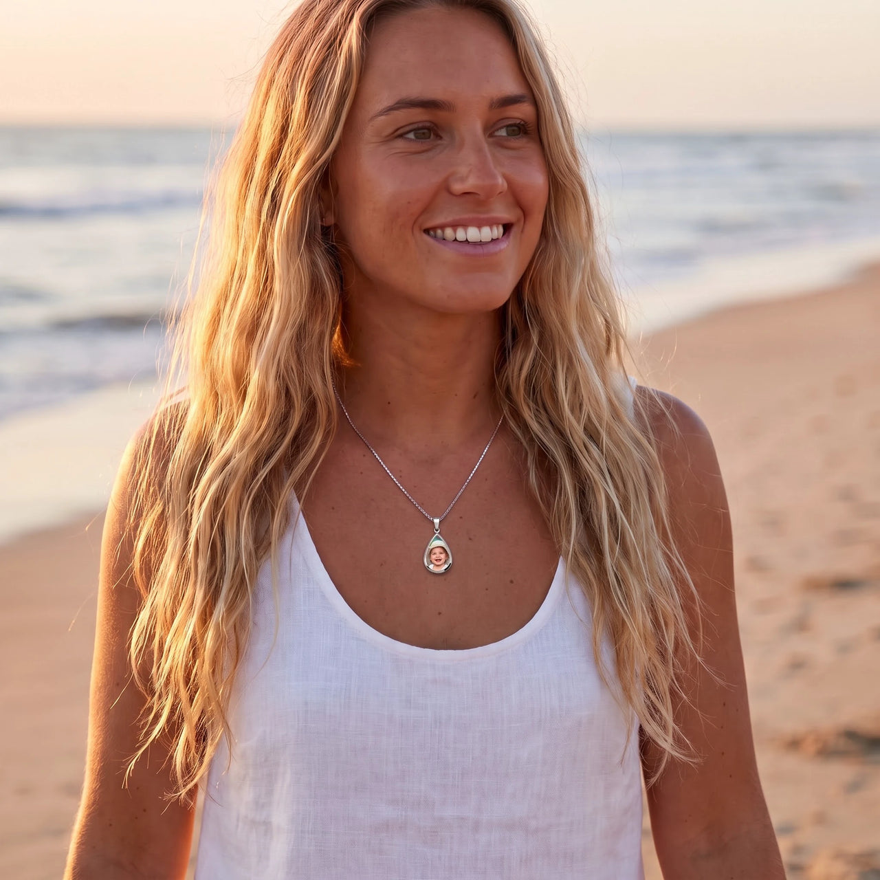 Woman on a beach at sunset wearing the silver secret drop photo necklace | SKU: TPH-DRPN-SILVER