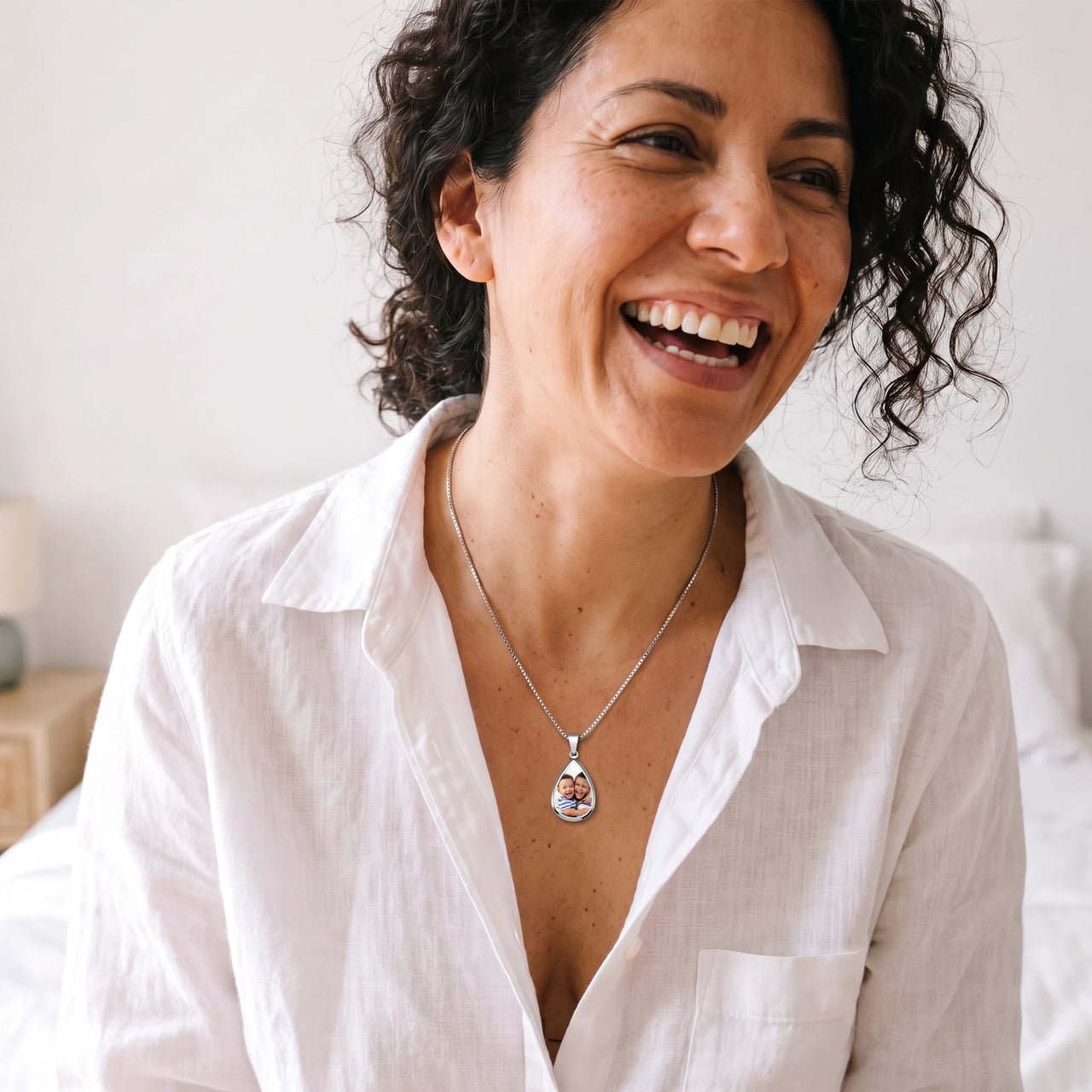 Woman with curly hair laughing in a white shirt, wearing the silver secret drop photo necklace | SKU: TPH-DRPN-SILVER
