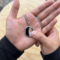 Thumbnail for Thumb warming the silver octagon pendant: the hidden photo appears under the thumb while the rest stays black | SKU: TPH-OCTN-SILVER
